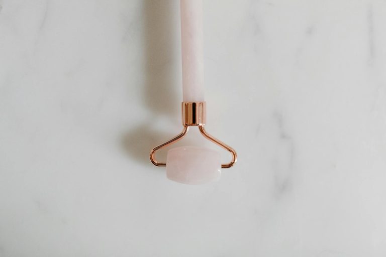 A close-up of a rose quartz facial roller on a marble surface, symbolizing luxury skincare.