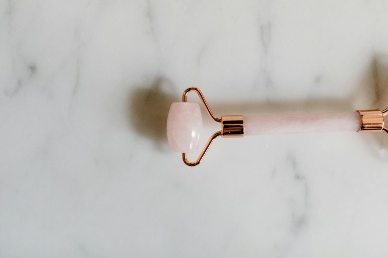 A rose quartz facial roller elegantly placed on a marble surface, emphasizing luxury and skincare.