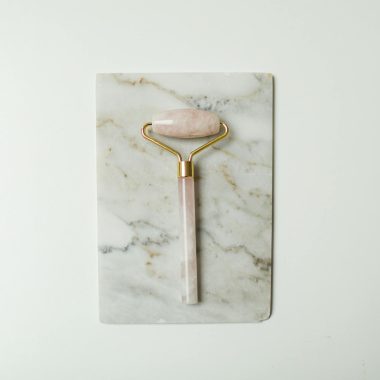 A rose quartz facial roller on a marble slab, perfect for skincare routines.