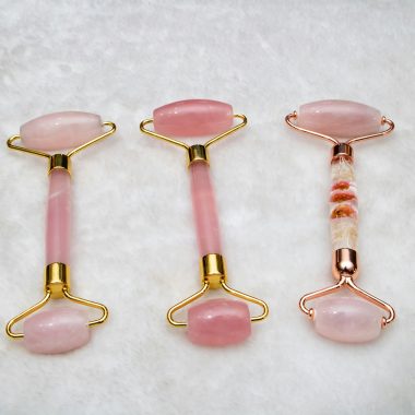 Three pink jade face rollers elegantly arranged, showcasing skincare luxury.