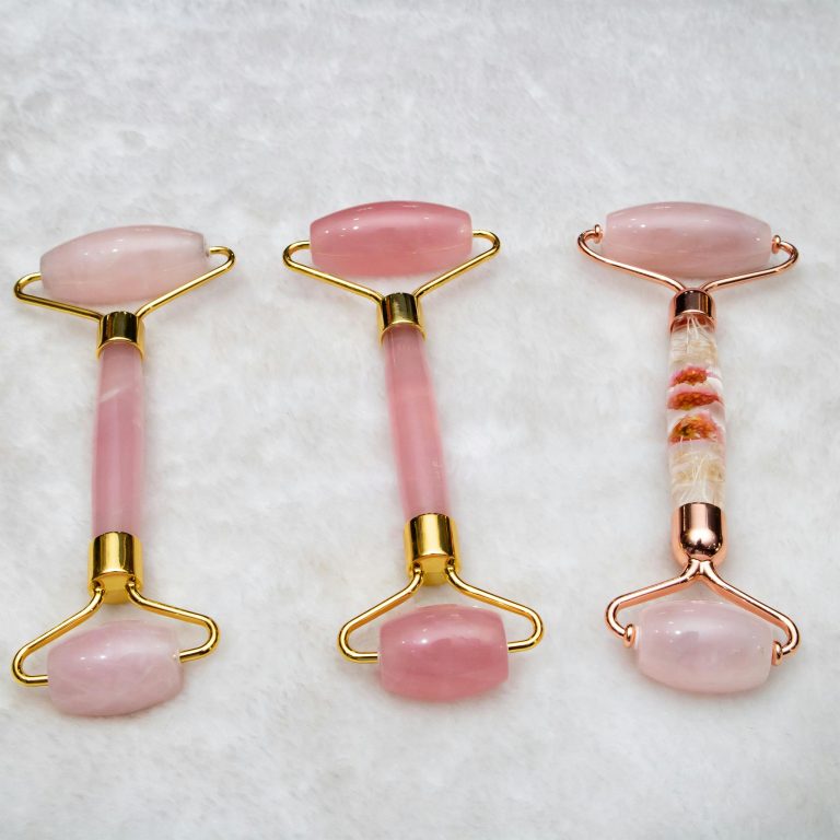Three pink jade face rollers elegantly arranged, showcasing skincare luxury.